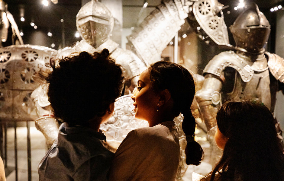 A family with children looking at the armors in the museum's exhibition at the Royal Armoury.