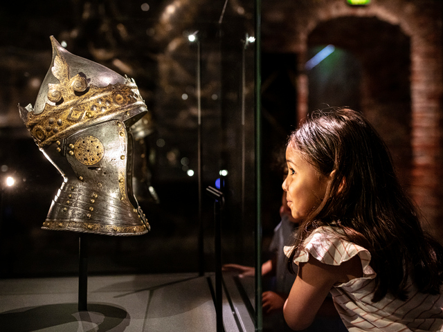 Ett barn som tittar på Gustav Vasas krönta hjälm.