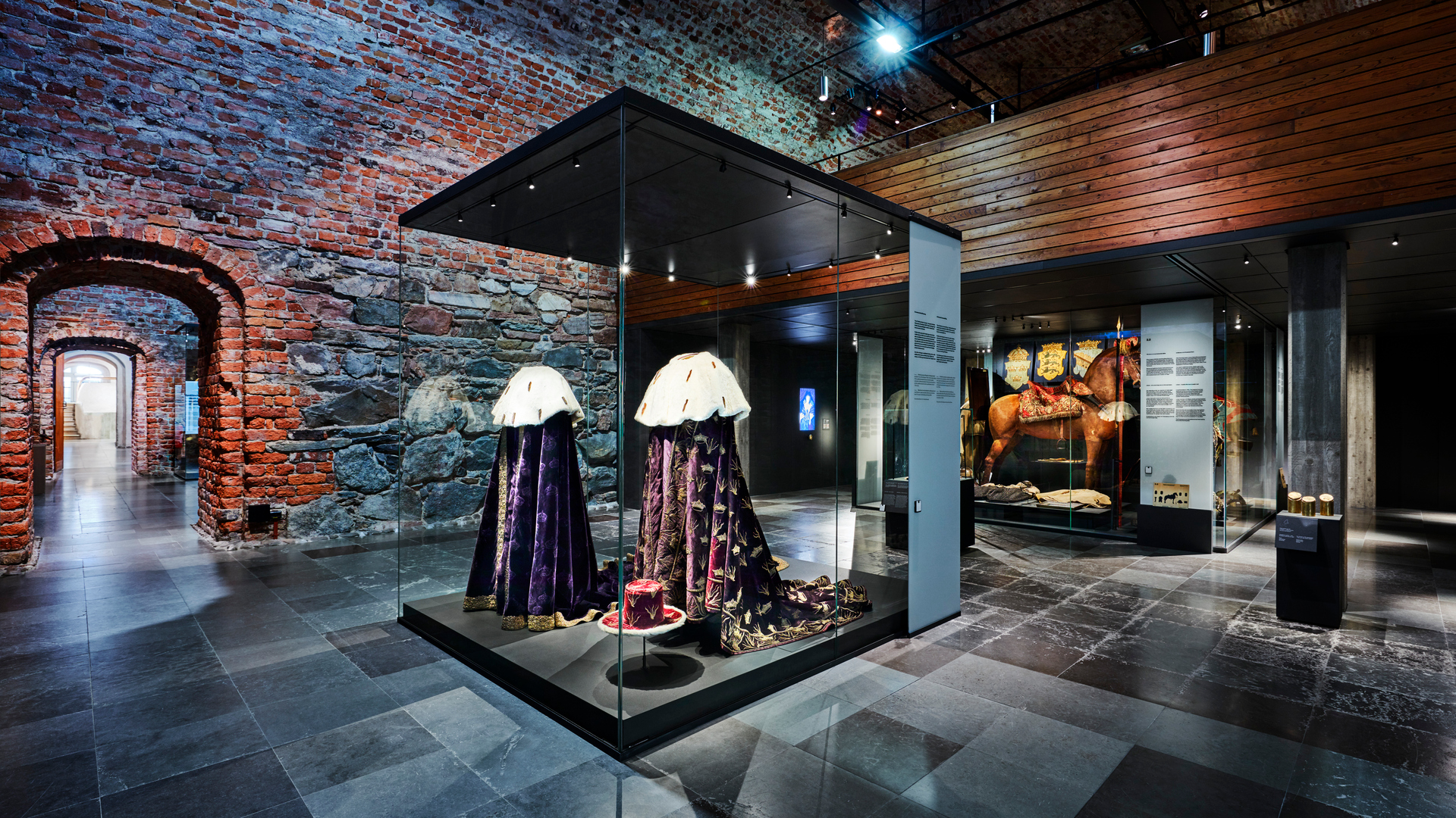 A museum case in The Royal Armoury with two royal velvet mantles.