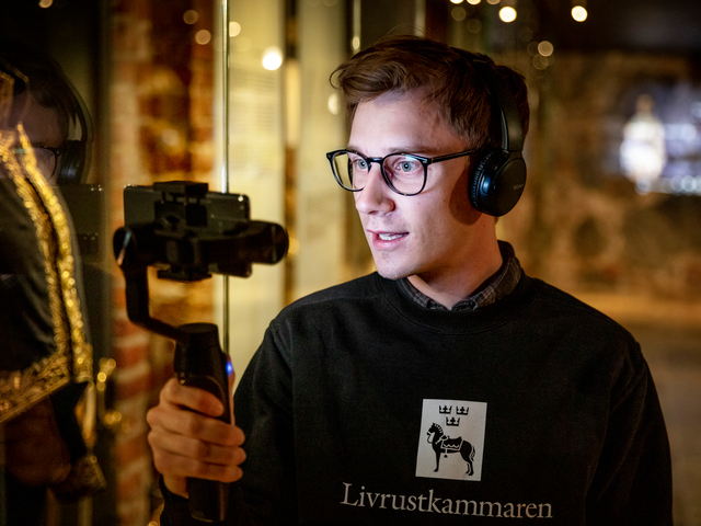 Livrustkammarens pedagog som håller i en kamera och utför en digital visning i museets utställning