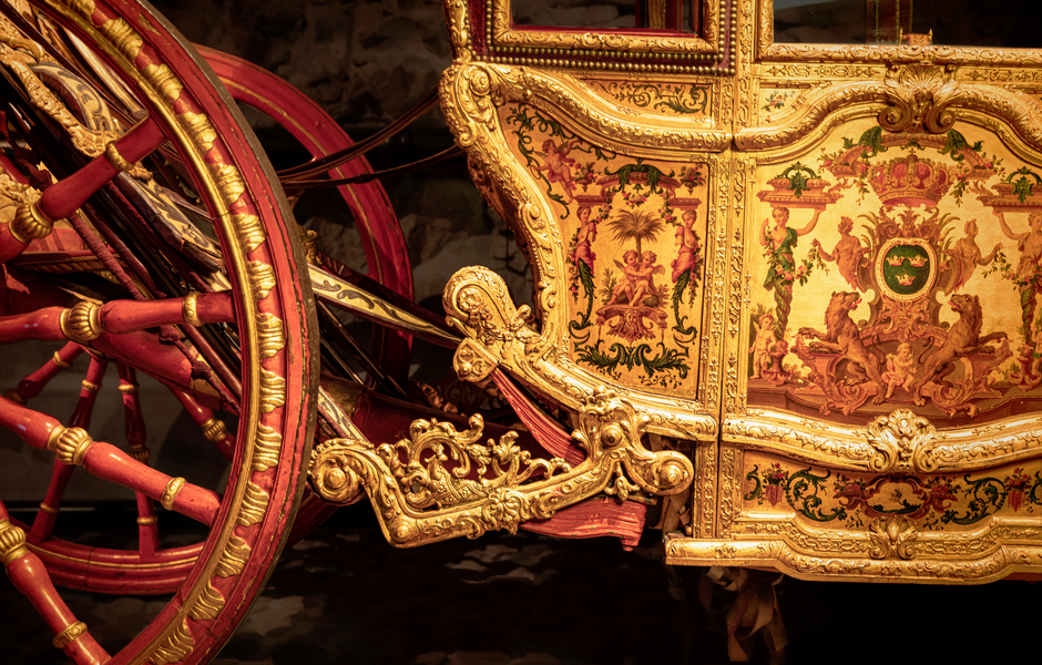 En gyllene vagn med röda hjul och riklig dekor.