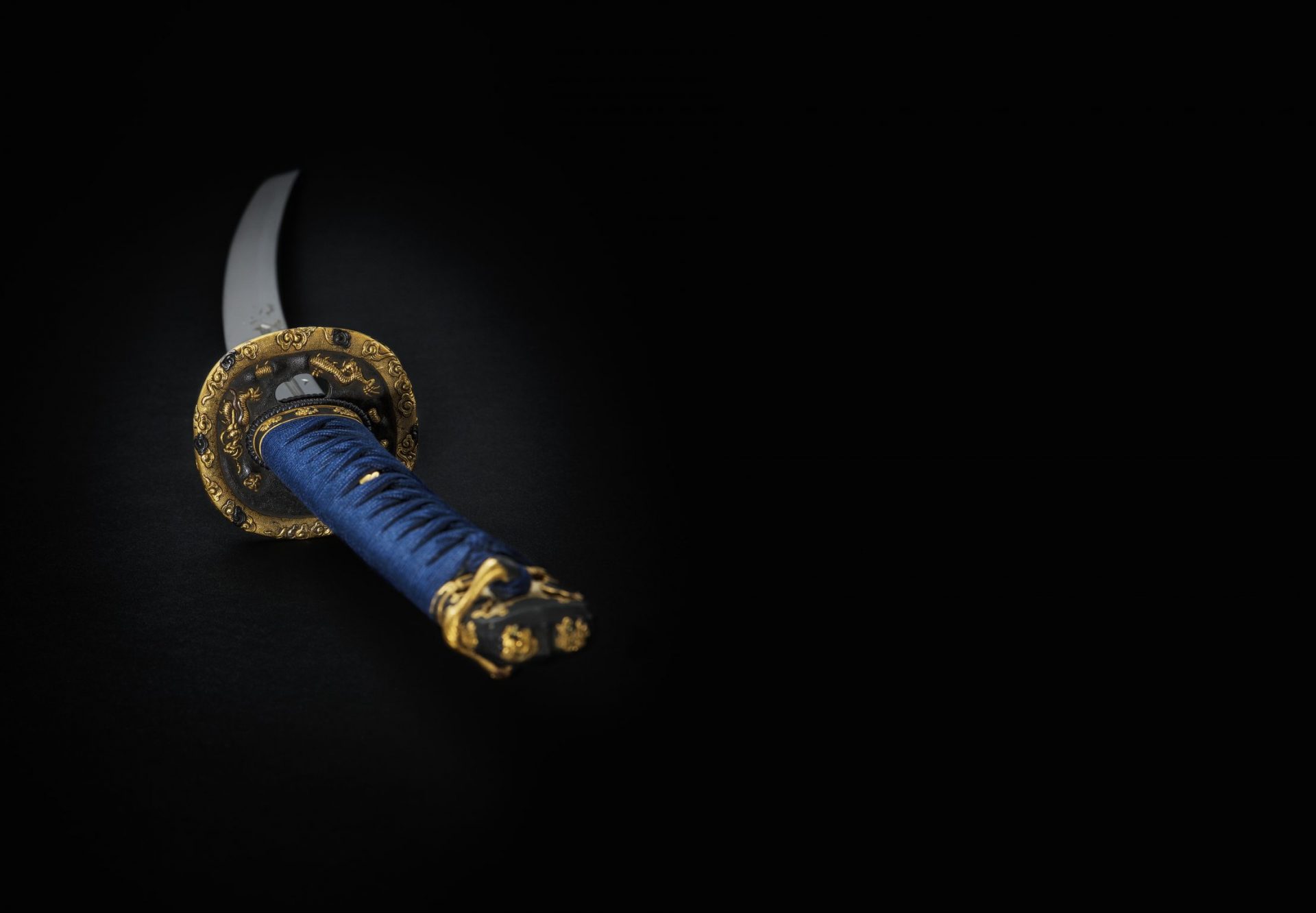 Närbild av svärd med blått handtag och guldinslag.