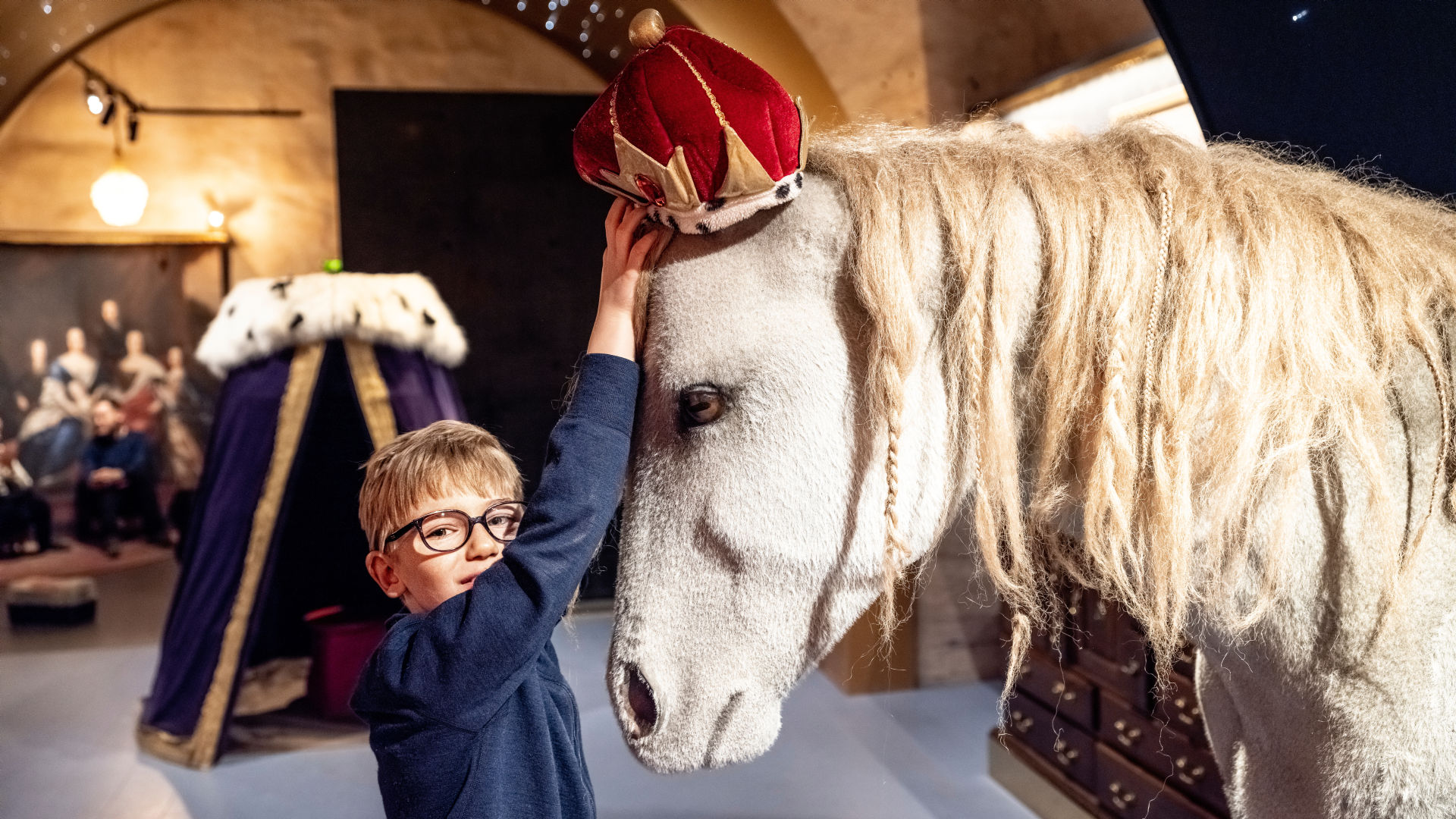 A kid playing with a lifesize toy horse