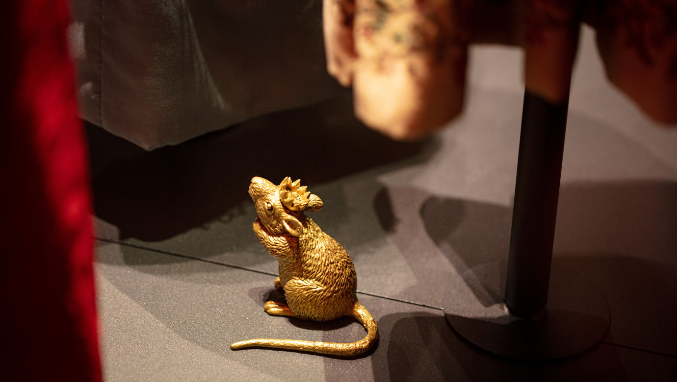 A golden little mouse with a crown on his head.