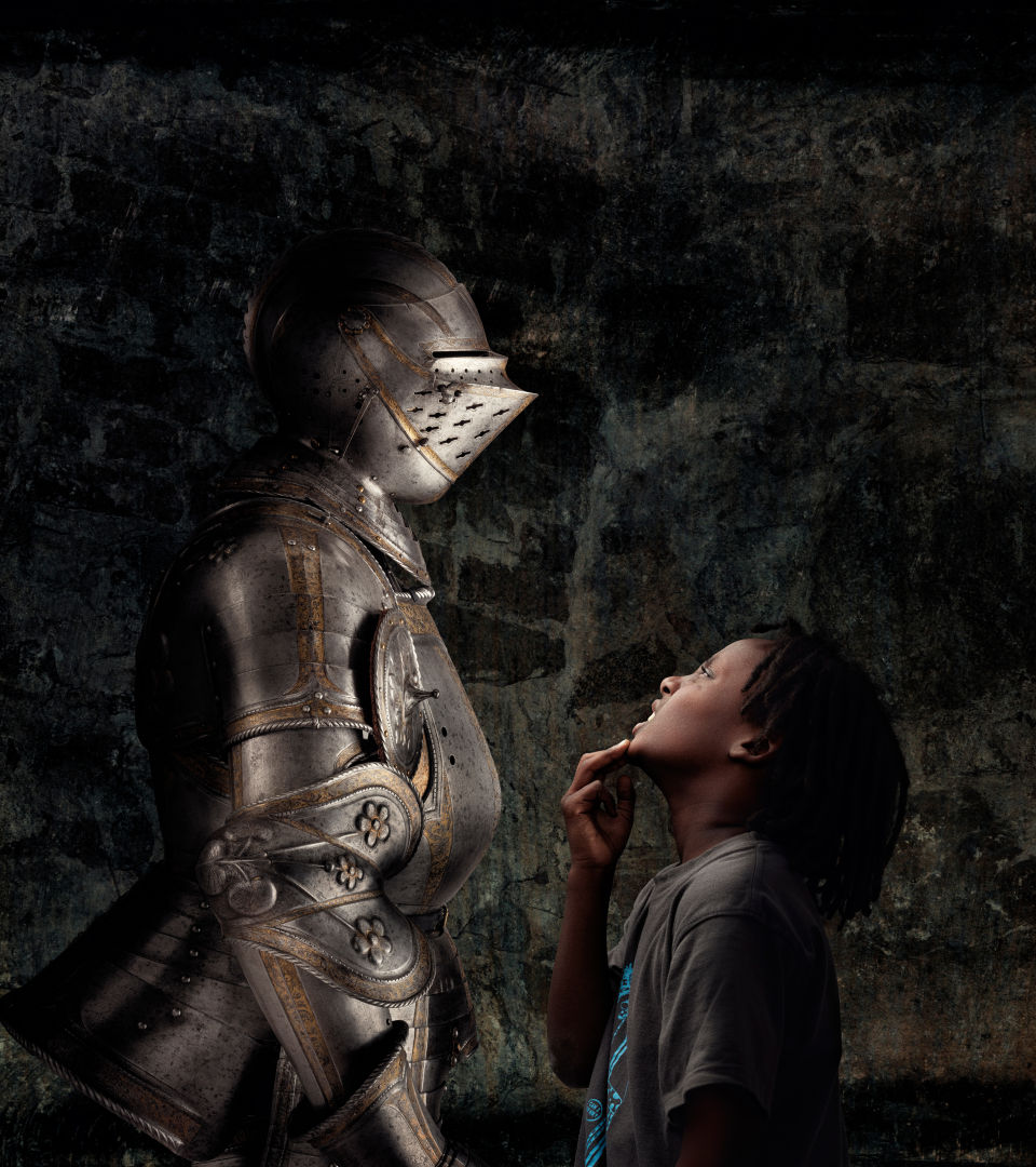 A child is looking up at a suit of armor.