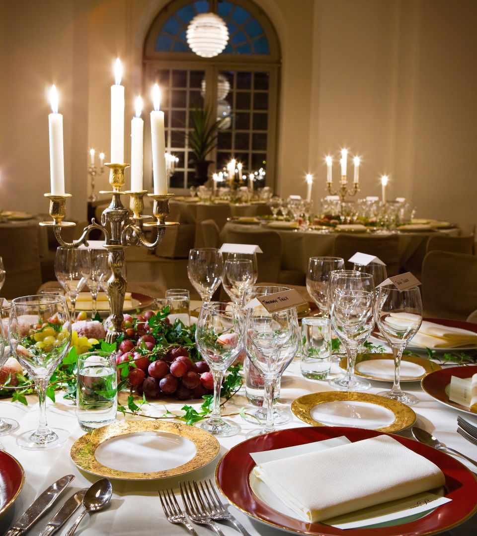 Juligt uppdukat bord i Stensalen på Livrustkammaren med kandelabrar med ljus som lyser stämningsfullt.