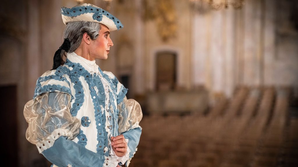 A person in historic clothes, looking out at the audience