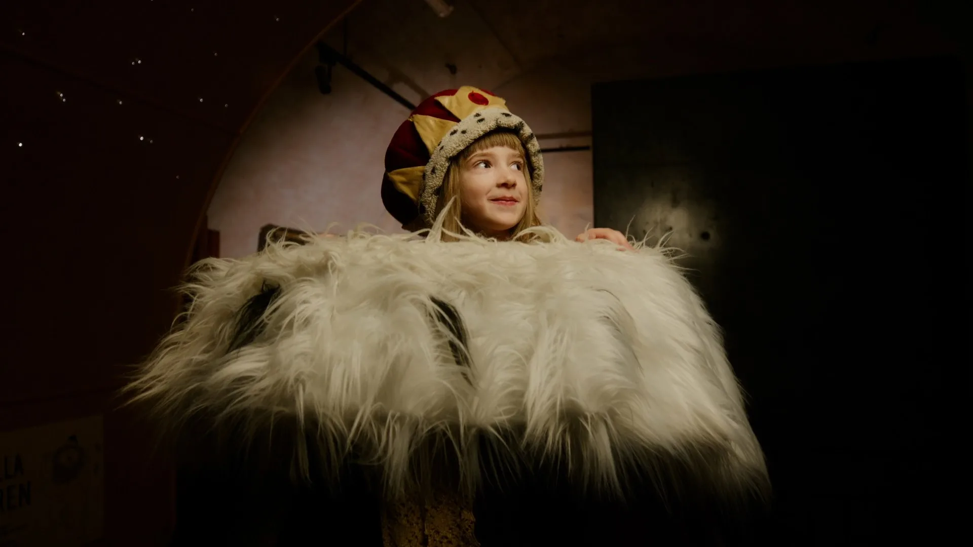 Ett barn som är utklätt till kung, men mantel och krona