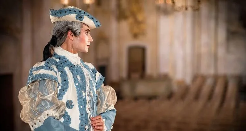 Person in historical clothing stands on a stage