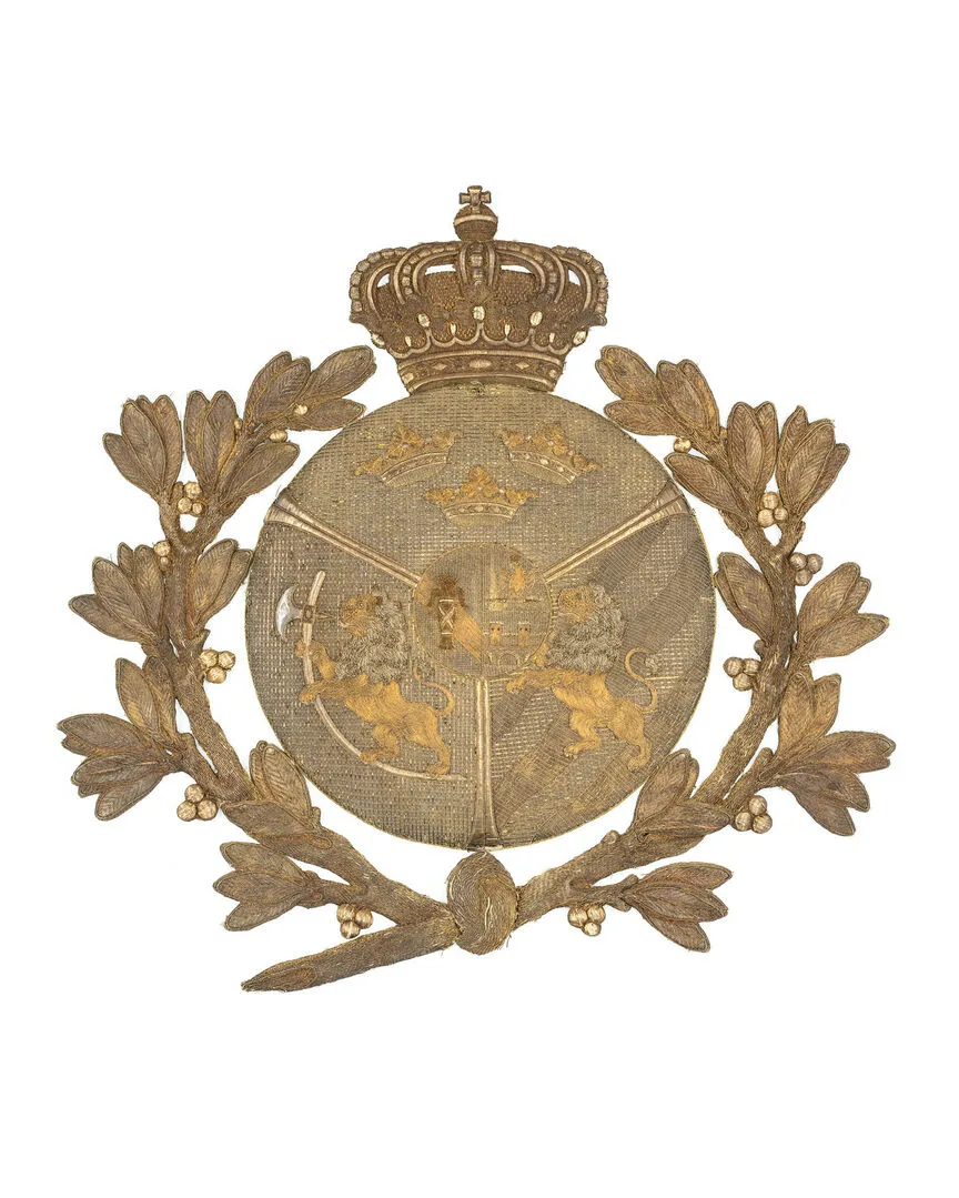 Ett gyllene heraldiskt emblem prytt med en kunglig krona över en rund sköld. Skölden visar två lejon och tre kronor, omgiven av en lagerkrans.
