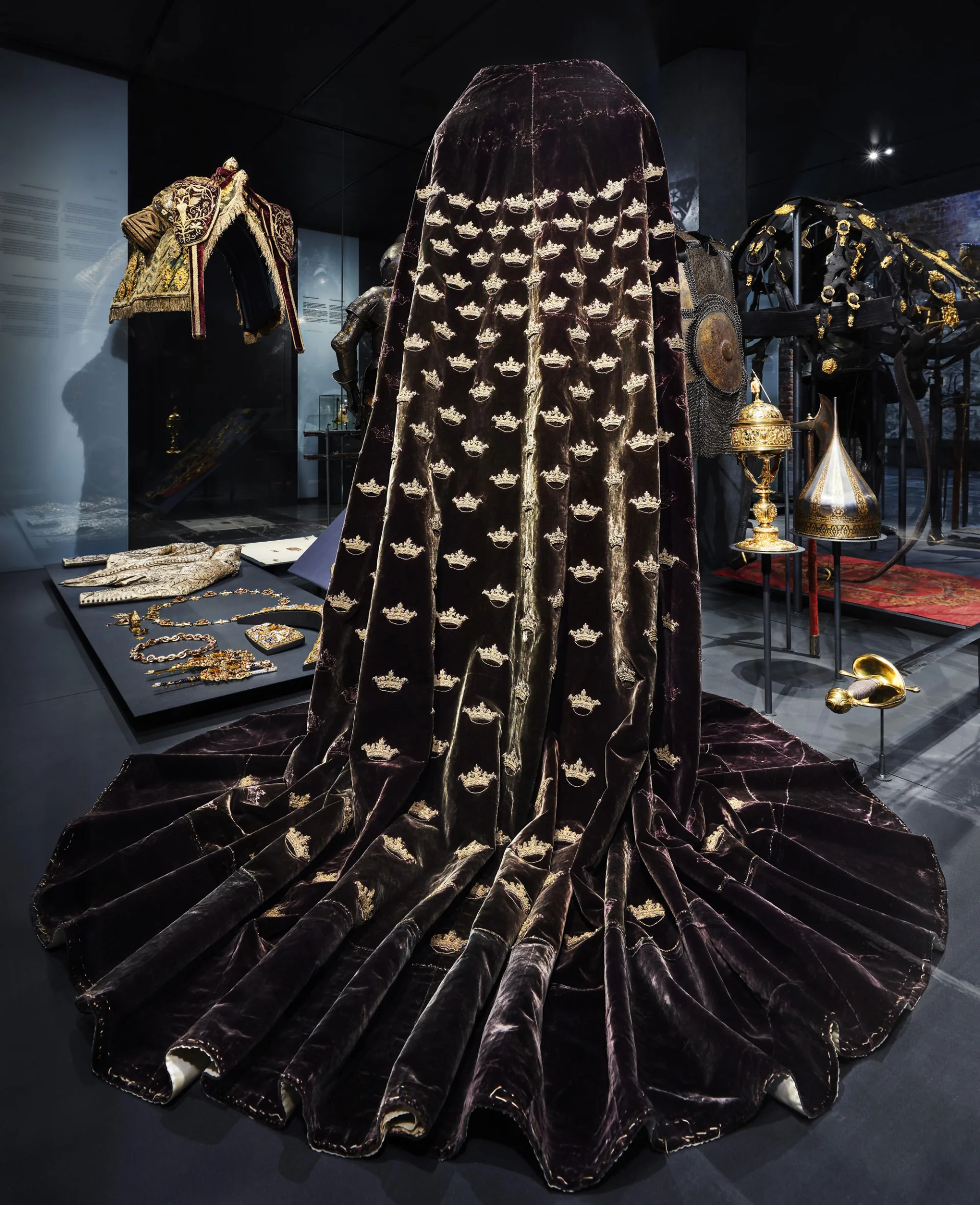 Erik XIV:s kröningsmantel i en museimonter bland andra kungliga föremål på Livrustkammaren.
