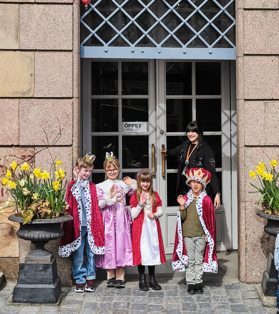 Children dressed as kings and princesses at the entrance of the Royal Armoury with museum staff
