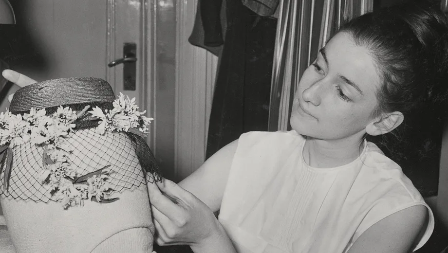 Milliner arranges the veil on a hat.